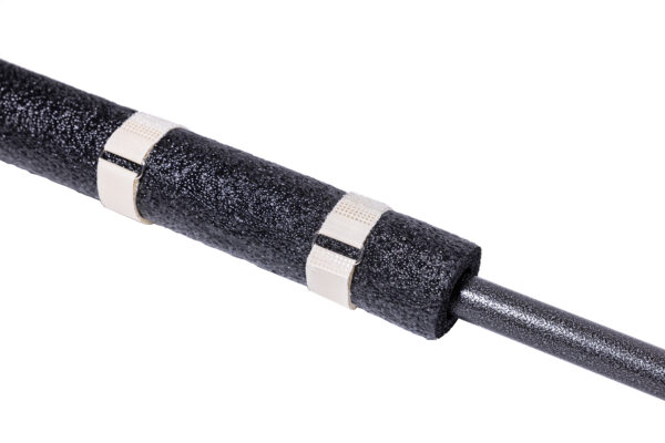 IMG_0098 - Speedtech International A close-up of a black foam pipe insulation tube secured with two SPEEDWRAP® High Temp Cinch Straps, wrapped around a metal pipe on a white background.