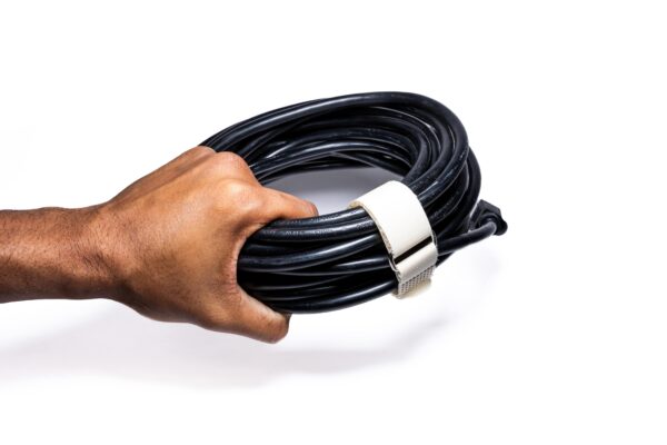KVNR6808-min - Speedtech International A hand holds a coiled black cable secured with a white SPEEDWRAP® High Temp Cinch Strap, against a white background.
